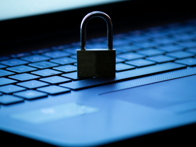 Um cadeado físico sobre o teclado de um laptop, representando proteção e segurança cibernética.